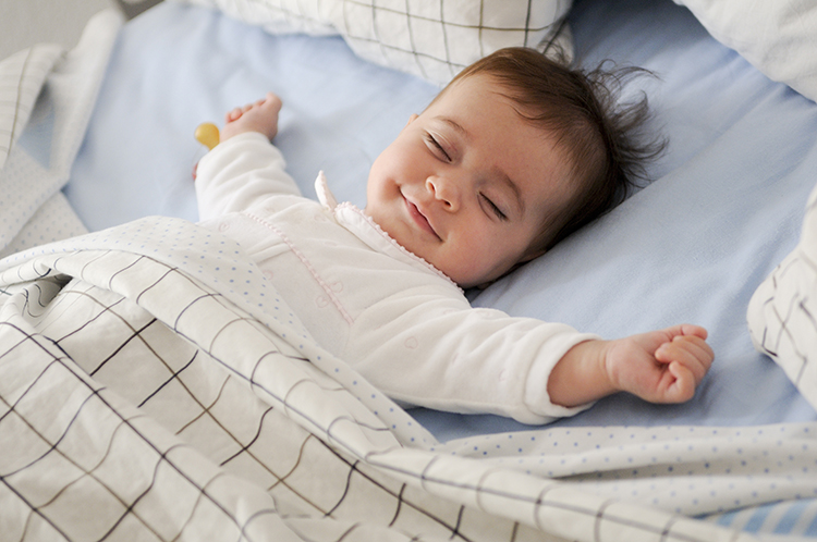 Smiling baby lying on a bed sleeping