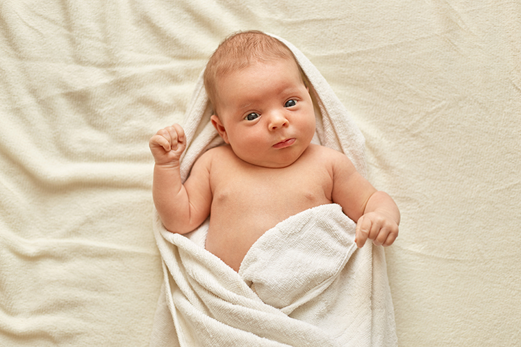 Newborn baby wearing towel watching