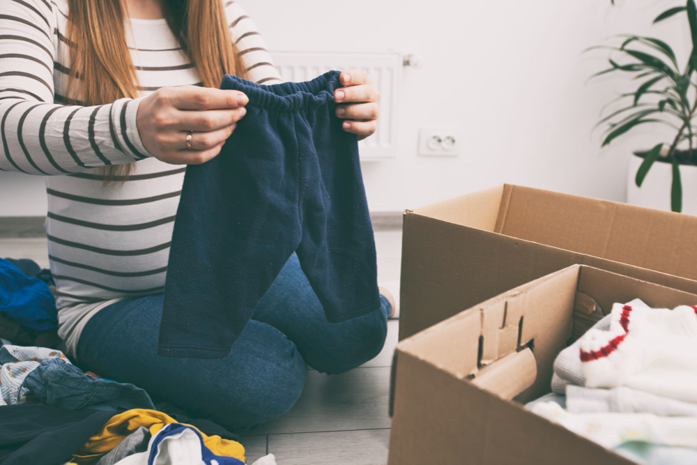 pregnant woman sorting baby clothes