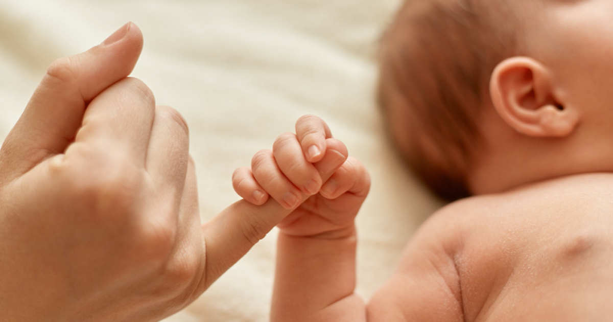baby holding finger in her palm
